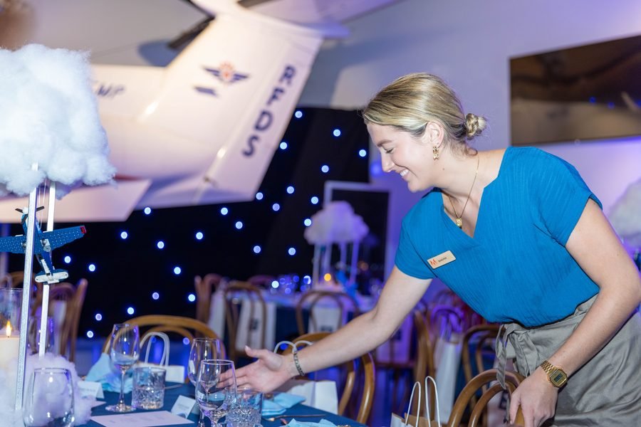 Event staff finishing a table setting before the doors open