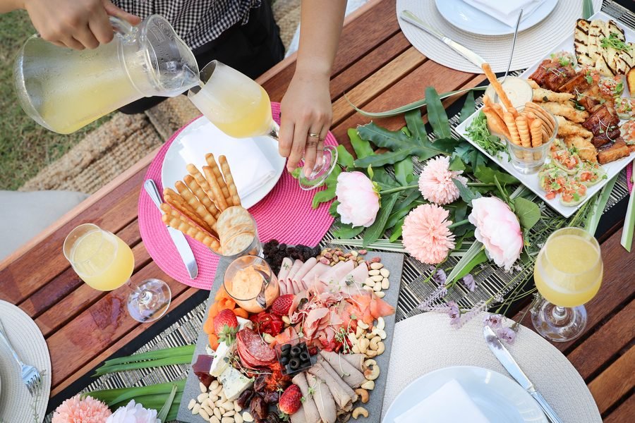 Overhead view of a hand pouring juice over a dressed grazing table