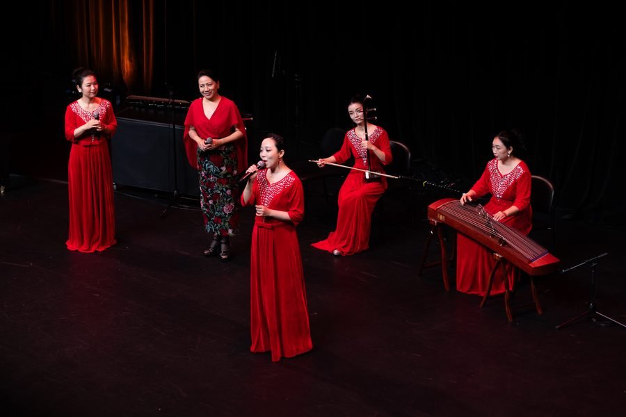 Musicians in red performing on the darkened stage