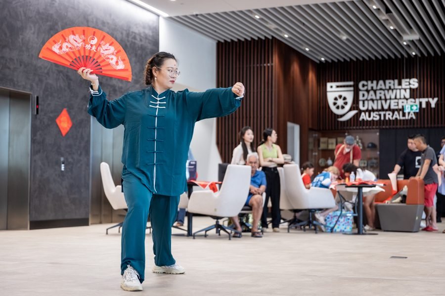Performer mid form beneath the university sign