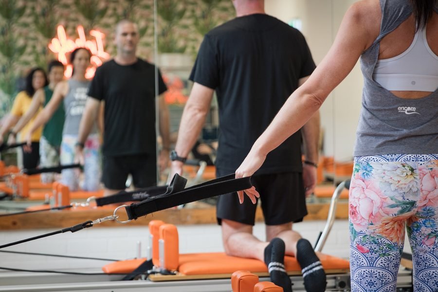 Instructor coaching a member through a set on the orange apparatus