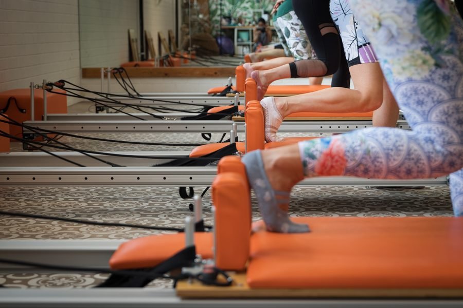 Row of feet braced on the footbars of the orange reformers