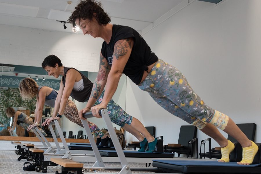 Member in a long plank over the reformer, mirror behind