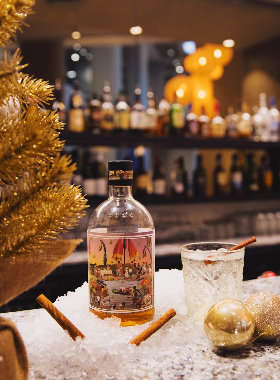 Gin bottle on the bar beside a gold tree and ice bucket
