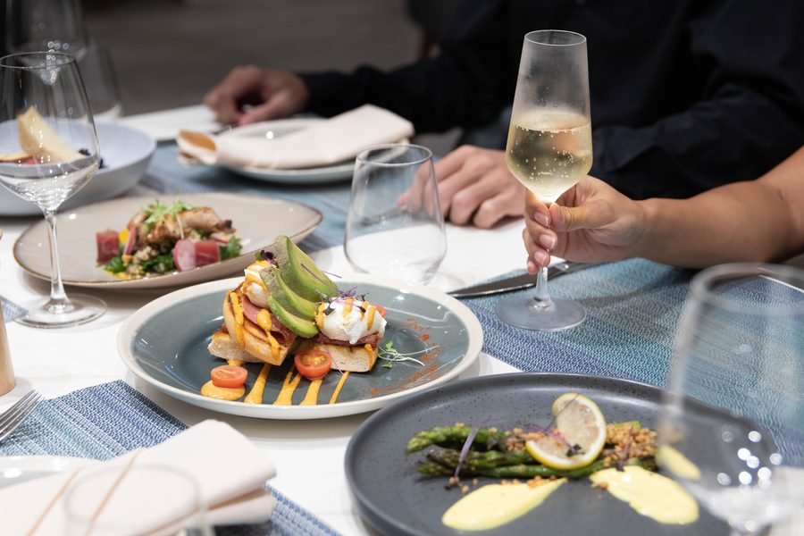 Two guests at a bright table with plated brunch and sparkling wine