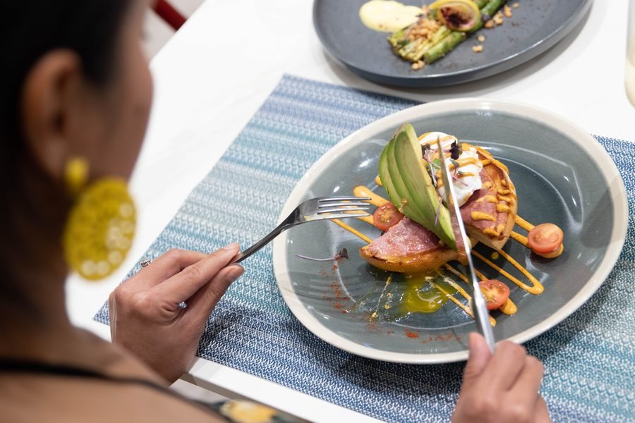 Guest lifting a forkful from a plated brunch dish