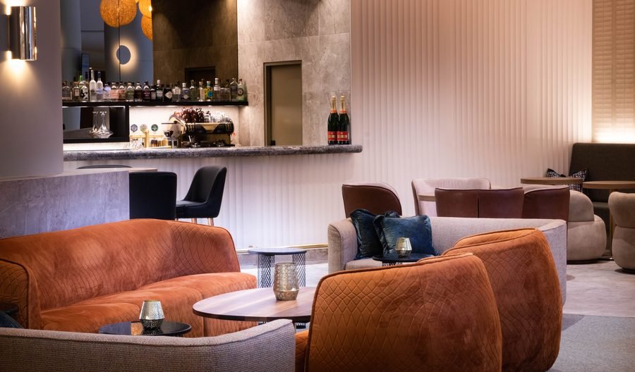 Lounge seating with a burnt orange sofa and the back bar behind