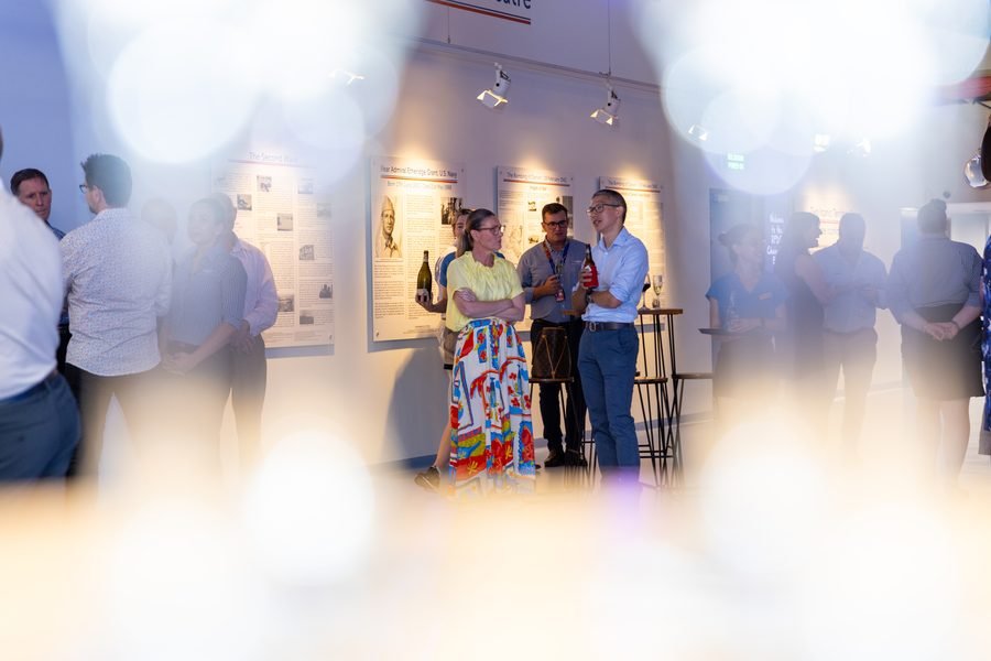 Crowd gathered in conversation, lights soft in the foreground