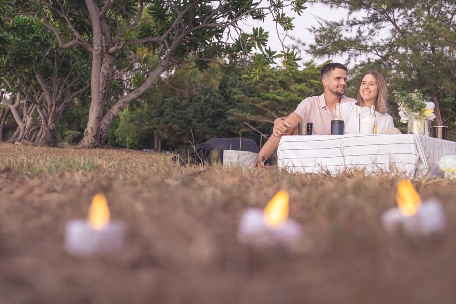 Couple seated at the picnic table with candles burning in the foreground