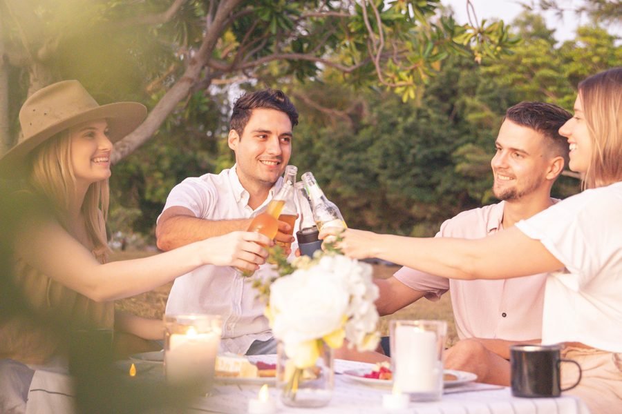 Friends reaching across the table for a toast at golden hour