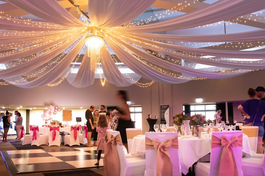 Expo floor beneath draped ceiling fabric and fairy lights