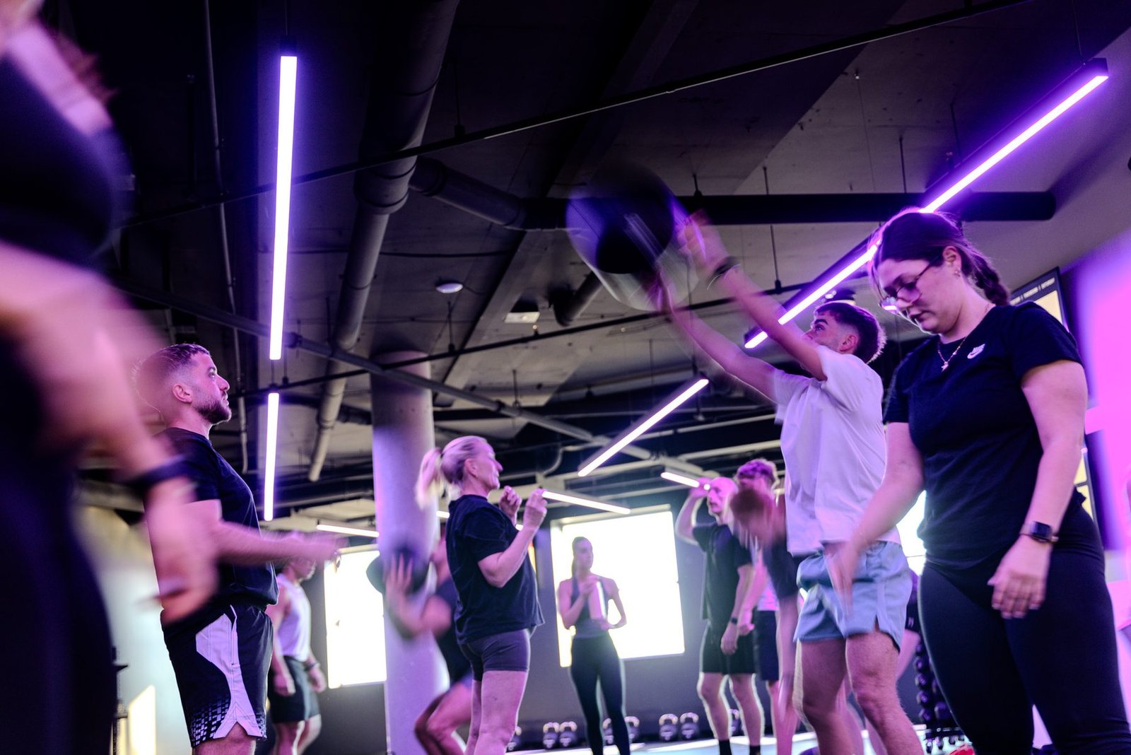 Coach working the floor with members under violet tube lighting